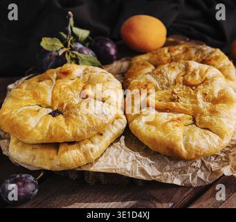 Freshly baked fruit galettes with apricots and plums, served on rustic wooden background Stock Photo