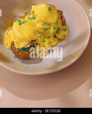 Delicious eggs benedict served on wholegrain toast, topped with creamy hollandaise sauce and garnished with chives Stock Photo