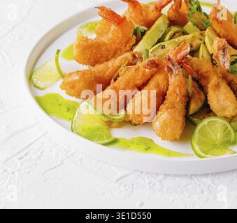 Golden fried shrimp served with slices of fresh lime and dipping sauce, garnished with herbs Stock Photo