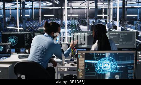 Data center coworkers having fun in office, using machine learning algorithms to analyze datasets. Server farm colleagues goofing around while using AI at work, workplace friendship concept, camera A Stock Photo