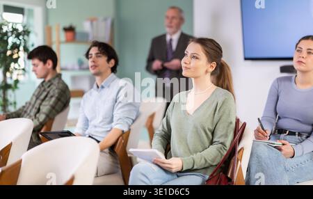 Students listening in lecture hall with professor in background Stock Photo