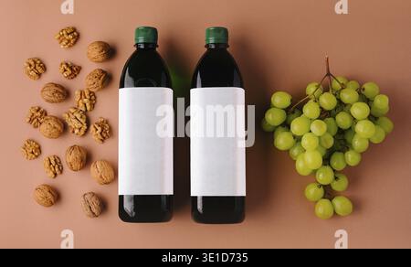 Two bottles of wine with blank labels are laying on a brown background surrounded by grapes and walnuts Stock Photo