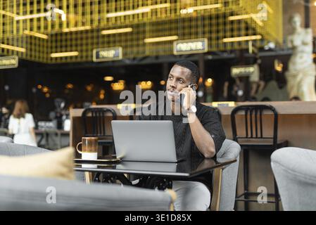 Portrait of handsome young black man using laptop computer in coffee shop Stock Photo