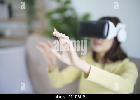 Young Asian woman wearing virtual reality touching air during the VR experience Future technology concept Stock Photo