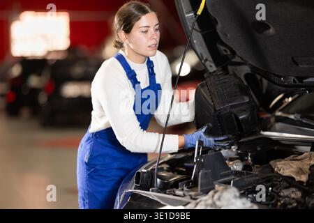 Female mechanic changing air filter in car engine Stock Photo