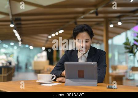 Portrait of Asian businessman sitting in coffee shop using digital tablet computer Stock Photo