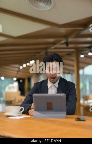 Portrait of Asian businessman sitting in coffee shop using digital tablet computer Stock Photo