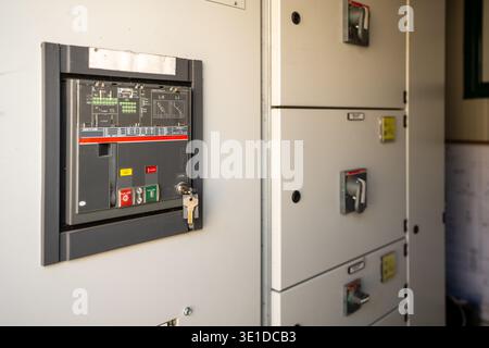 Close-up of an industrial electrical switchboard featuring a power circuit breaker. The image shows control buttons, a technical display, and a safety Stock Photo