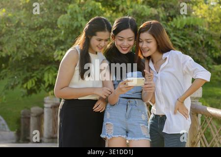 Portrait of three young Asian women as friends together relaxing at the park outdoors Stock Photo