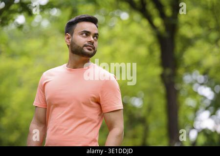Portrait of young handsome bearded Indian man at the park outdoors Stock Photo