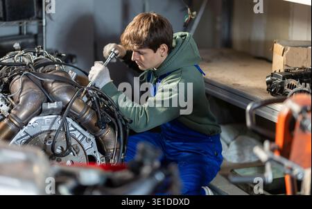 Young auto mechanic repairing an engine in garage Stock Photo