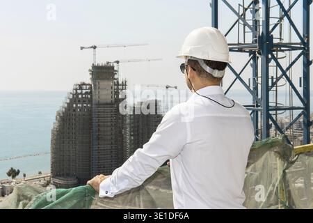 Young confident architect or businessman wearing hard hat looking on a construction site Stock Photo