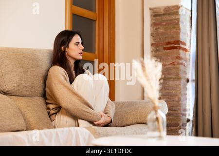 Young woman feeling sad contemplating while sitting on sofa Stock Photo