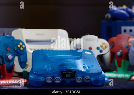 Nintendo 64 console with multiple colored controllers displayed in a retro gaming setup, showing an iconic piece of video game history and late 90s te Stock Photo