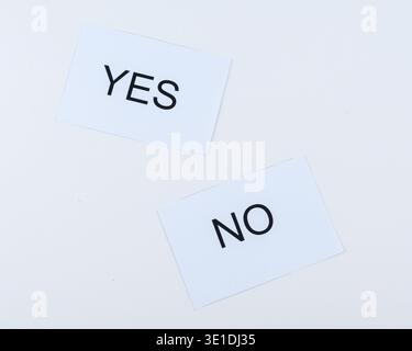 Tilted paper cards with YES and NO on white background, minimalist concept for choice, approval, rejection, voting, uncertainty and decision making. Stock Photo
