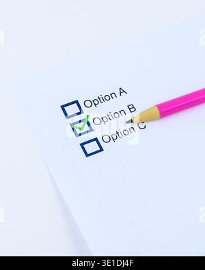 Checklist showing Option B selected with a green check mark and pink pencil on white paper, conceptual image for choice, selection, evaluation and dec Stock Photo