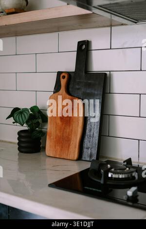 A contemporary kitchen features a sleek gas stove on a marble countertop, complemented by white subway tiles. Two decorative wooden cutting boards and Stock Photo