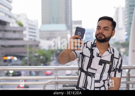 Portrait of young bearded Indian man exploring in the city outdoors Stock Photo