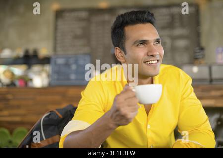 Portrait of young handsome Indian man sitting at the coffee shop Stock Photo