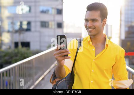 Portrait of young handsome Indian man on footbridge at the city Stock Photo