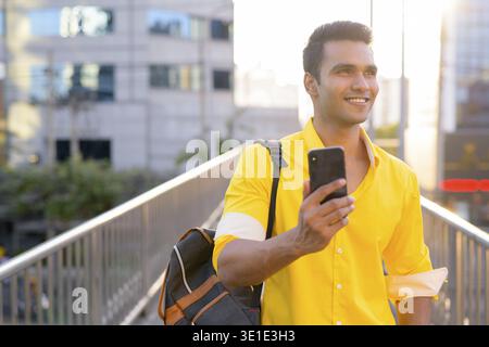 Portrait of young handsome Indian man on footbridge at the city Stock Photo