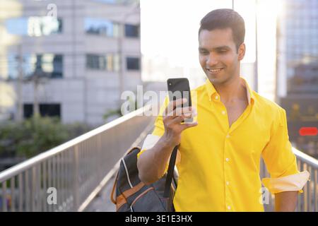 Portrait of young handsome Indian man on footbridge at the city Stock Photo