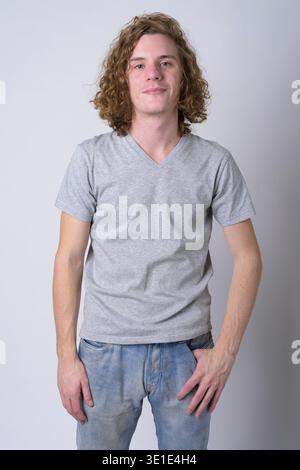 Studio shot of young handsome man with long curly hair against white background Stock Photo