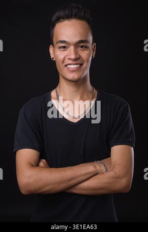 Studio shot of young handsome Indian man against black background Stock Photo