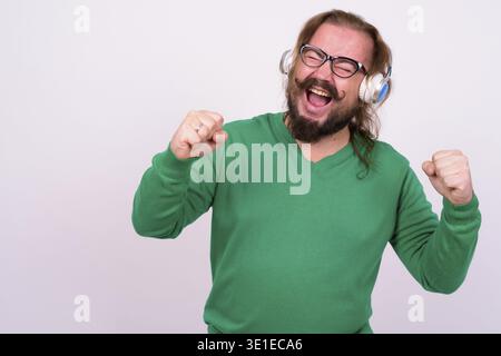 Portrait of overweight bearded man with mustache and long hair wearing green sweater against white background Stock Photo