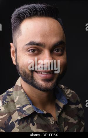 Studio shot of young bearded Indian man against gray background Stock Photo
