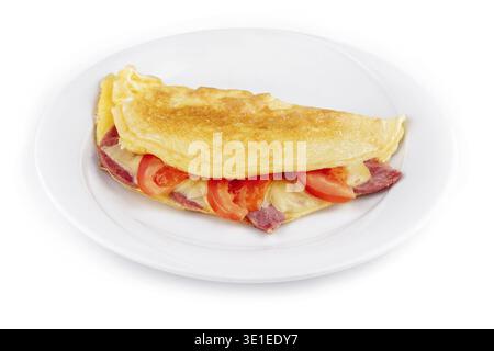 Delicious folded omelette filled with cheese, ham and tomatoes, served on a white plate, isolated on a white background Stock Photo