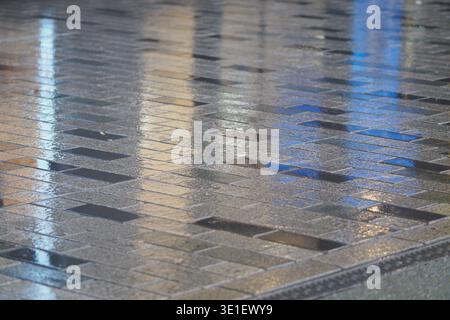 Rain falling on a tiled surface at night in the city Stock Photo