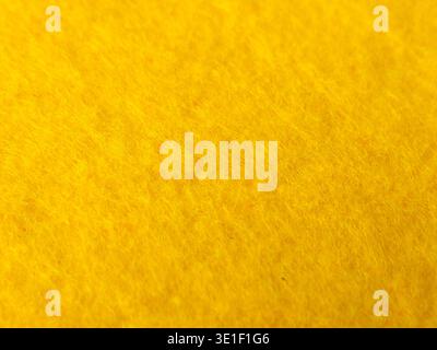 A high-resolution macro close-up showcasing the vibrant yellow texture of a felt or fleece fabric. Stock Photo