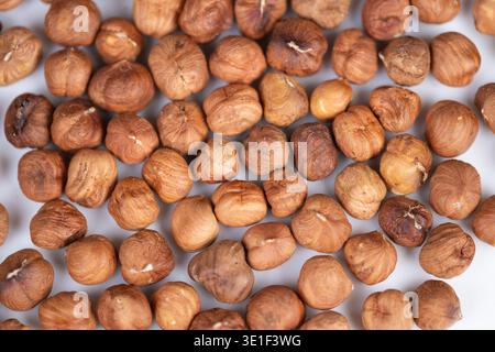Closeup hazelnut kernels on white backdrop, warm rustic tones, scattered arrangement, textured skins and subtle shadows, cozy snack mood for packaging Stock Photo