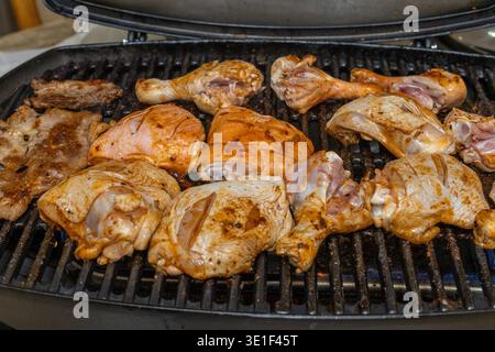 Assortment of marinated chicken pieces and pork cuts cooking on a hot grill Stock Photo
