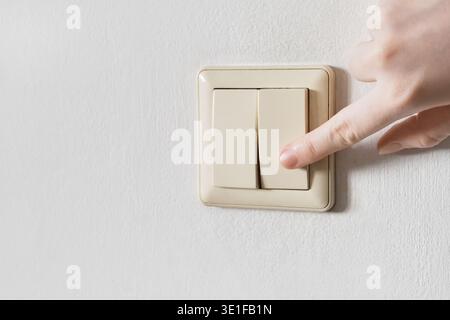 Hand pressing an electrical wall switch controlling energy and power Stock Photo