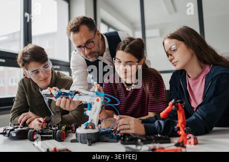 High school students working on robotics project with their teacher. Stock Photo