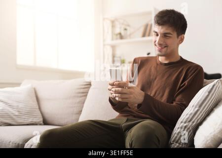 Young man with smartphone at home Stock Photo