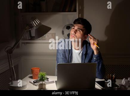 Thoughtful man with laptop at home office at night Stock Photo