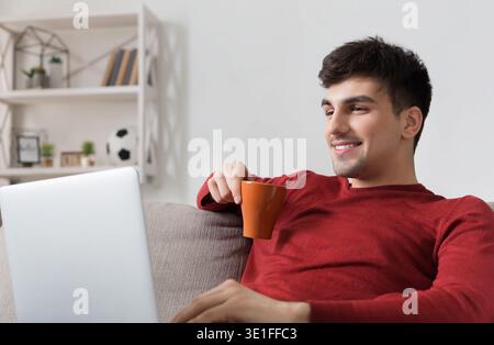 Man with laptop sitting on sofa at home Stock Photo
