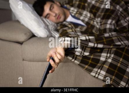 Man sleeping in front of television on the couch Stock Photo