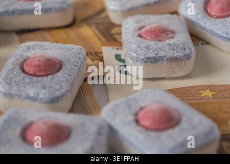 Dishwasher detergent tablets lying on euro currency banknotes against a white background Stock Photo