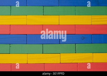 Close-up of a wall made from brightly colored wooden toy blocks arranged in a neat geometric pattern and texture, suitable for a background Stock Photo