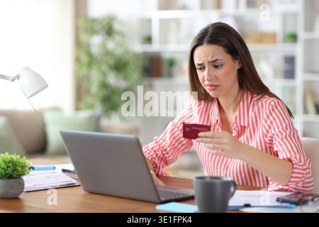 Disappointed freelance worker buying online with credit card checking laptop working at home Stock Photo