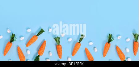 Banner with carrots made from colored jute rope and small Easter eggs on blue background with copy space Stock Photo