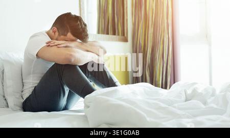 Depressed man sitting on his bed Stock Photo