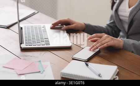 Accountant Using Laptop And Sending Message On Phone Stock Photo