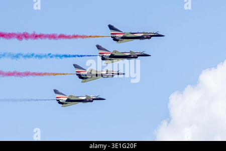 Aerial view of fighter jets soaring through the sky, leaving trails of vibrant red, blue, and yellow smoke in their wake, Changi Exhibition Centre, Si Stock Photo