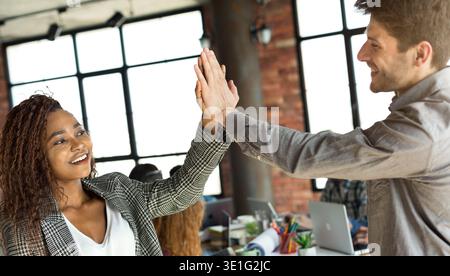 Diverse colleagues giving high five at office meeting Stock Photo