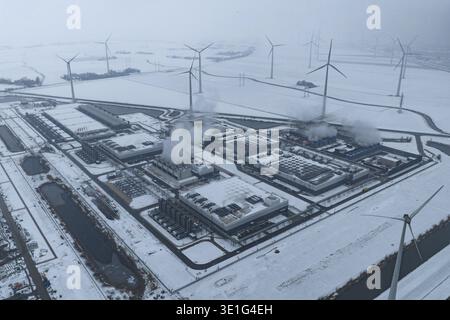 Aerial view of a large ai data center processing complex surrounded by active wind turbines on a snowy day, Eemshaven, Netherlands. Stock Photo